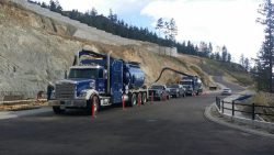 Line of D&L hydrovac trucks on a hillside road project